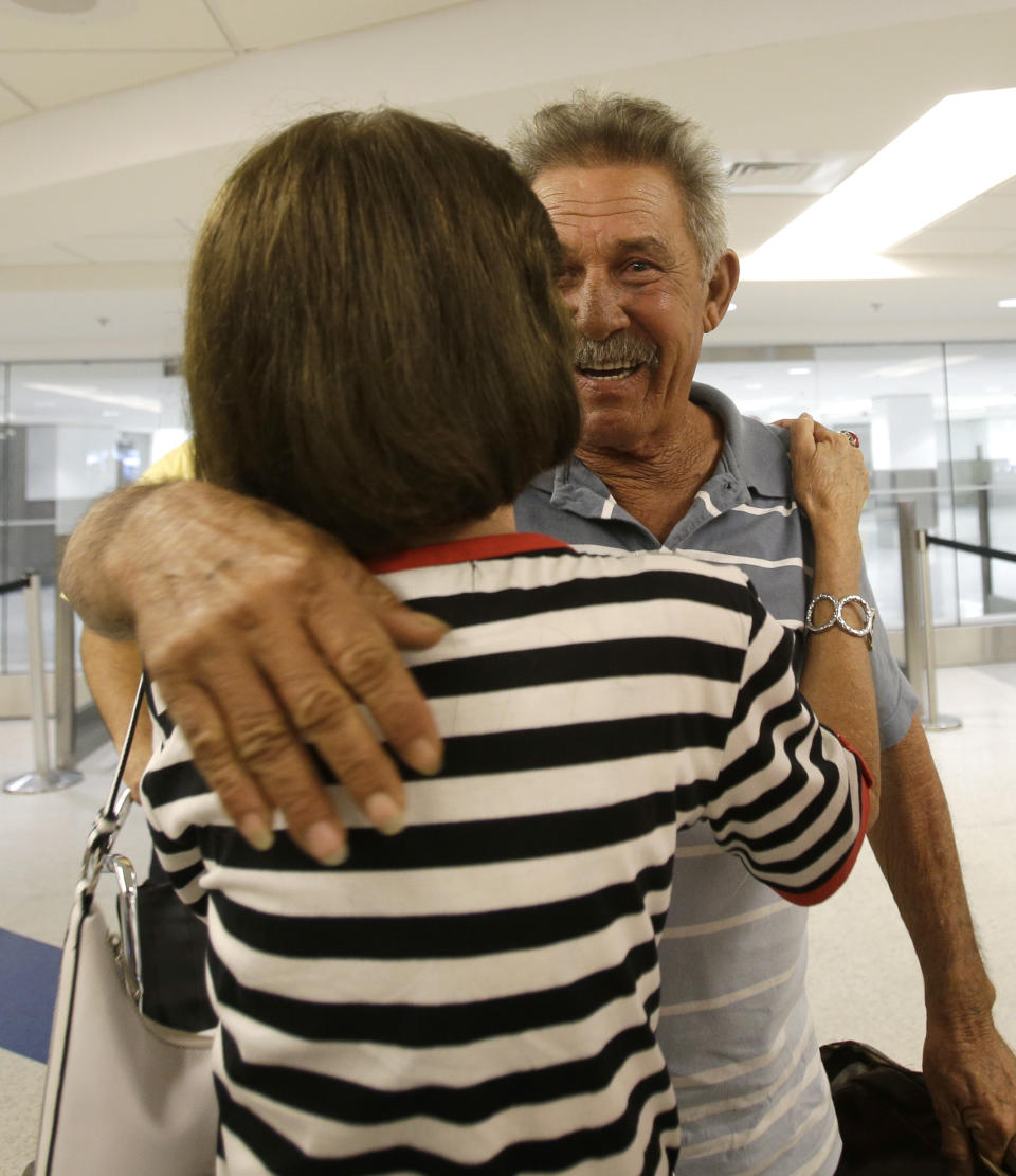 In this Sept. 11, 2013, photo, Benito Perez is welcomed by friend Rogelia Ventura at his arrival at Miami International Airport, in Miami. Perez, who had never been on a plane, is one of thousands of Cubans traveling under new laws making travel slightly easier. (AP Photo/Alan Diaz)