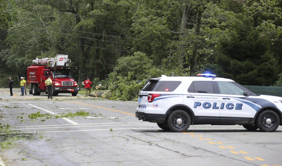A crew works to remove a downed tree from blocking Route 138 in South Kingstown, R.I., Sunday, Aug. 22, 2021. Strong winds from Tropical Storm Henri toppled many trees in the southern regional of the state. (AP Photo/Stew Milne)