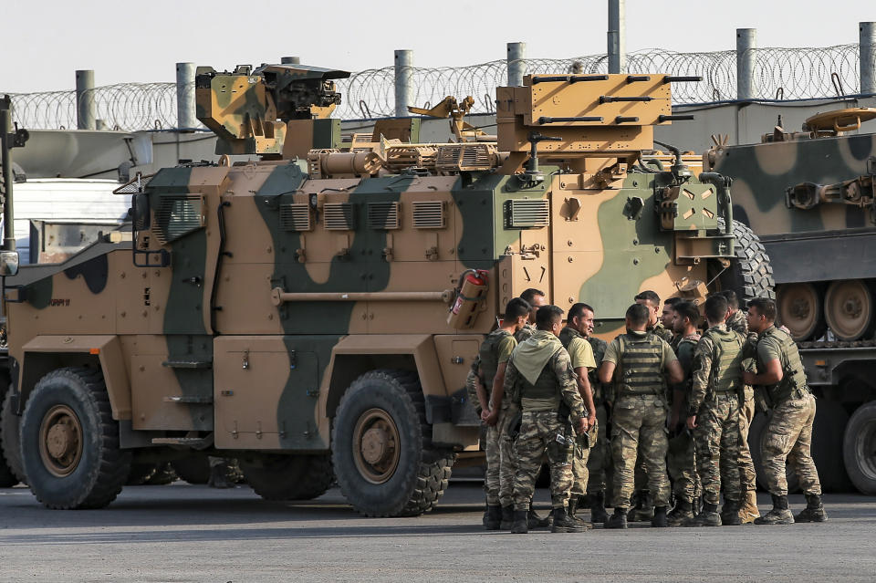 Turkish soldiers prepare to enter Syria aboard an armoured personnel carrier at the border with Syria in Karkamis, Gaziantep province, southeastern Turkey, Tuesday, Oct. 15, 2019. Turkey defied growing condemnation from its NATO allies to press ahead with its invasion of northern Syria on Tuesday, shelling suspected Kurdish positions near the border amid reports that Syrian Kurds had retaken a key town. (AP Photo/Emrah Gurel)