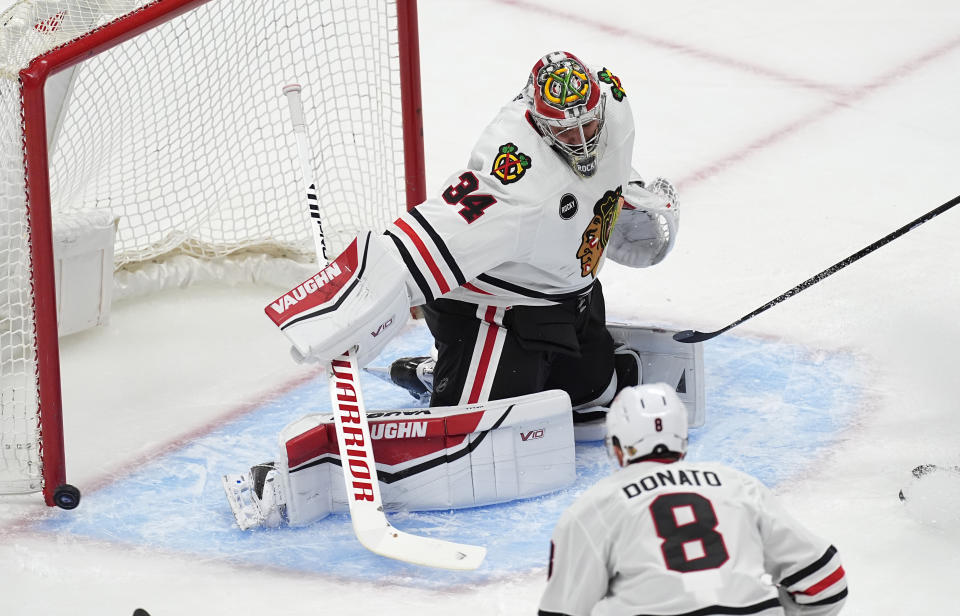 Chicago Blackhawks goaltender Petr Mrazek, back, deflects a shot as center Ryan Donato looks on in the first period of an NHL hockey game against the Colorado Avalanche, Monday, March 4, 2024, in Denver. (AP Photo/David Zalubowski)