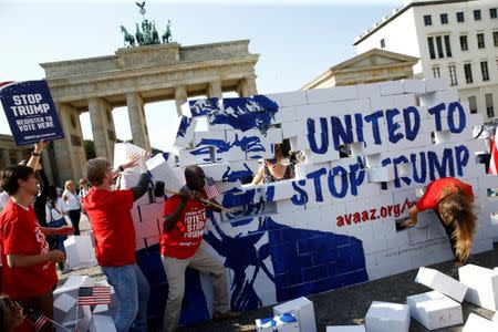 Campaigners pose on a 'United To Stop Trump' cardboard wall in front of the Brandenburg Gate to urge Americans living abroad to register and vote in Berlin, Germany, September 23, 2016. REUTERS/Axel Schmidt TPX IMAGES OF THE DAY