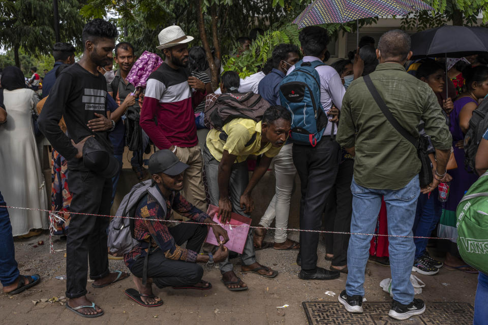 People wait in queue to get their passports outside Department of Immigration & Emigration in Colombo, Sri Lanka, Monday, July 18, 2022. Bankruptcy has forced the island nation's government to a near standstill. Parliament is expected to elect a new leader Wednesday, paving the way for a fresh government, but it is unclear if that's enough to fix a shattered economy and placate a furious nation of 22 million that has grown disillusioned with politicians of all stripes. (AP Photo/Rafiq Maqbool)