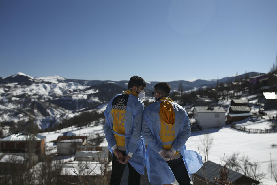 Dr. Yasin Kaya, left and health worker Yusuf Duran, right, members of the the Koyulhisar Public Health Center vaccination team, take a break as they walk to vaccinate 85-year-old Ibrahim Yigit at his house in the isolated village of Gumuslu in the district of Sivas, central Turkey, Friday, Feb. 26, 2021. (AP Photo/Emrah Gurel)