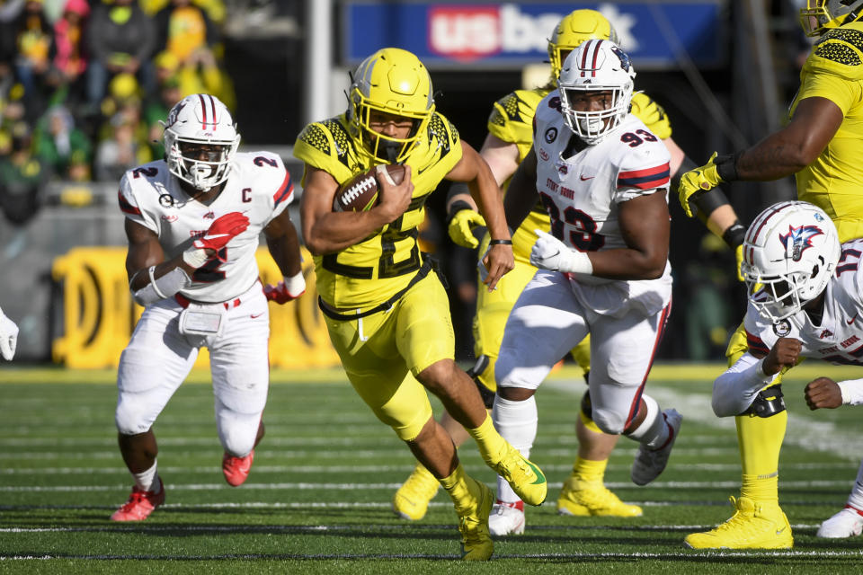 Oregon running back Travis Dye (26) runs past Stony Brook defensive lineman Casey Williams (2) and Stony Brook defensive lineman Dakar Edwards (93) during the first quarter of an NCAA college football game Saturday, Sept. 18, 2021, in Eugene, Ore. (AP Photo/Andy Nelson)