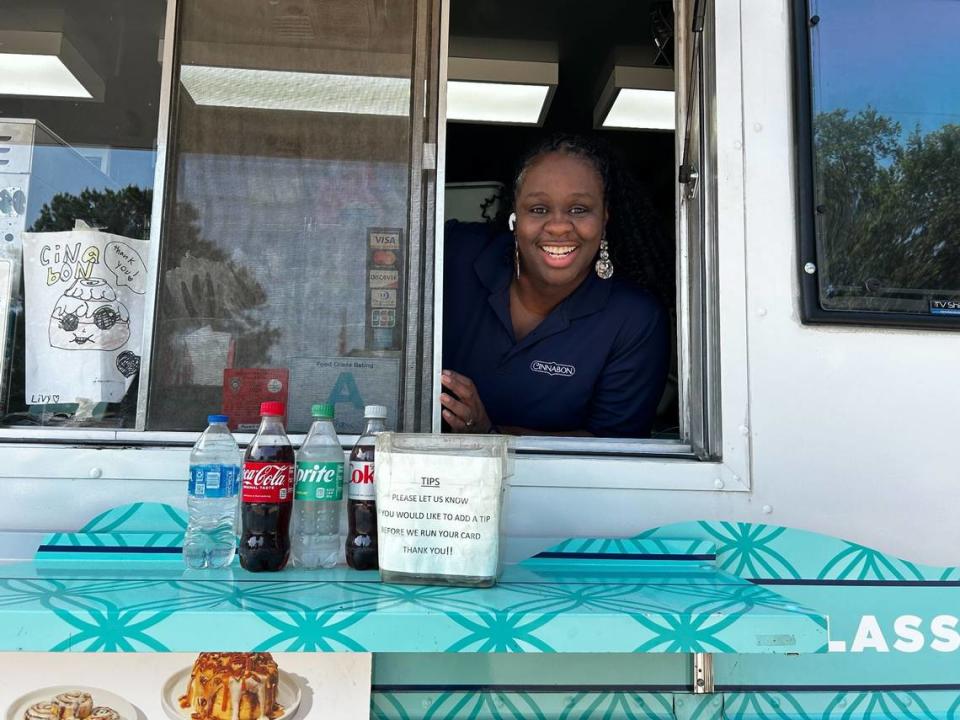 Monique Frazier smiles from the window of her Cinnabon food truck that she’s operated since 2022