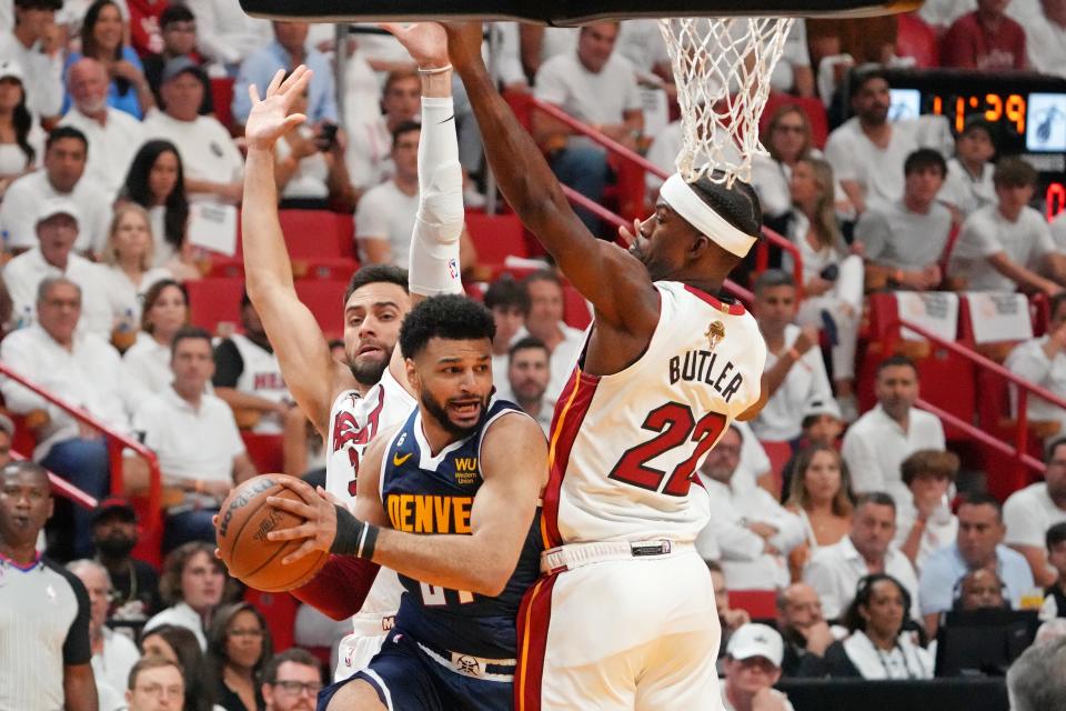 Denver Nuggets guard Jamal Murray passes the ball while defended by Miami Heat forward Jimmy Butler and guard Max Strus.