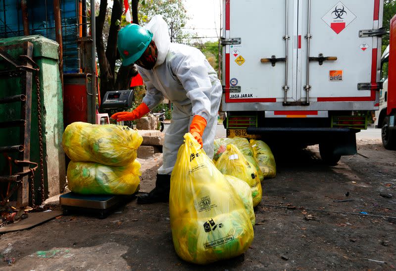 An incinerator company worker wearing protective suit prepares bags of medical waste to be loaded into a truck in Jakarta
