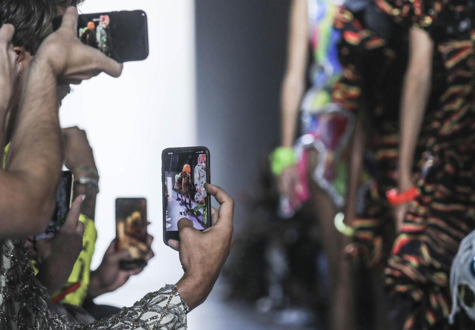 Guests grab cellphone photos of models in the latest fashion creation from Jeremy Scott, during New York's Fashion Week, Friday, Sept. 6, 2019. (AP Photo/Bebeto Matthews)