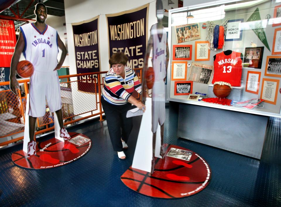 Judi Warren, Indiana's first Miss Basketball and member of the undefeated 1976 Warsaw state championship team, moves life-size cutout figures of Indiana basketball greats back into place at the Indiana Basketball Hall of Fame in New Castle on Saturday, April 26, 2008 after she introduced inductees into the 2008 Indiana Basketball Hall of Fame.