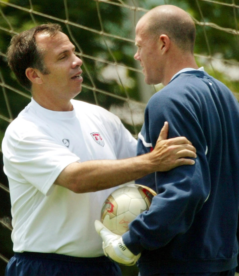 U.S. coach Bruce Arena (L) holds goalkeeper Brad Friedel during the  team training in Seoul June 11, 2002. USA will play Poland on June 14  in its last match of the first round of the World Cup Finals.  REUTERS/Shaun Best    SB/JD