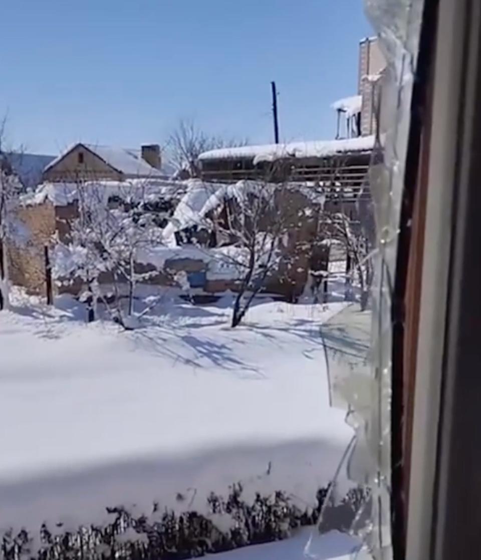 Snow on buildings through a broken window and with a blue sky