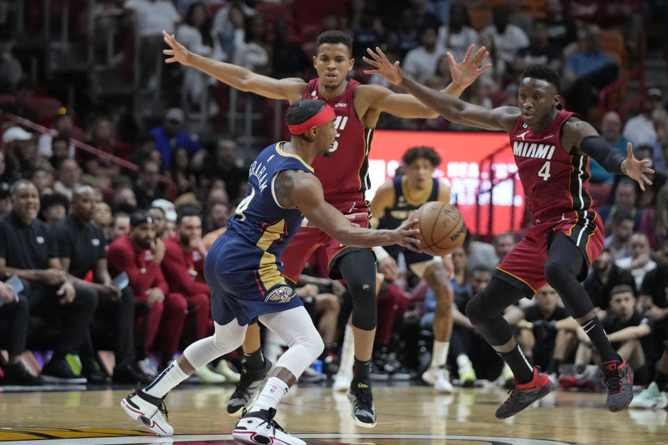New Orleans Pelicans guard Devonte' Graham, foreground, passes past Miami Heat guard Victor Oladipo, right, and center Orlando Robinson (25) during the first half of an NBA basketball game, Sunday, Jan. 22, 2023, in Miami. (AP Photo/Wilfredo Lee)
