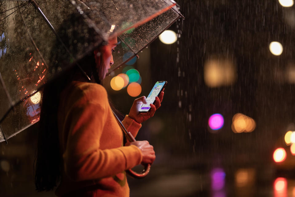 A woman uses an iPhone XS Max in the rain.