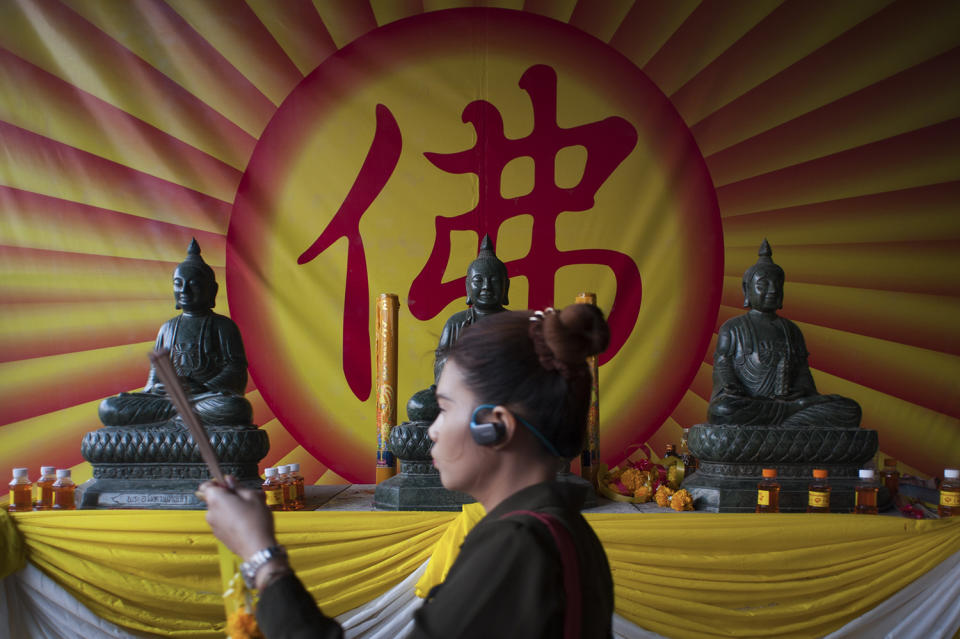 A woman walk in front of a Buddhist statue during the Lunar New Year celebrations at Wat Mangkon Kamalawat in Chinatown, Bangkok , Thailand on January 28, 2017. (Anusak Laowilas/NurPhoto via Getty Images)