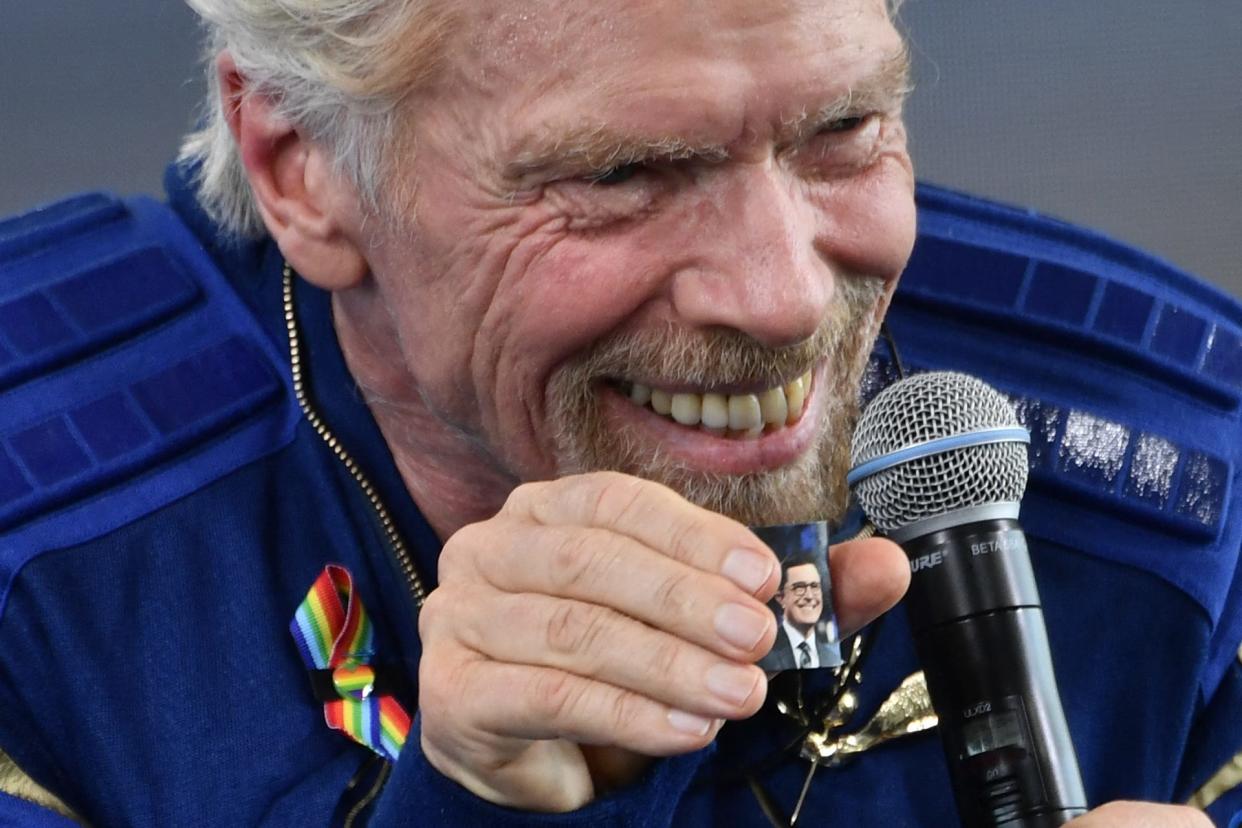 richard branson holds photo of stephen colbert