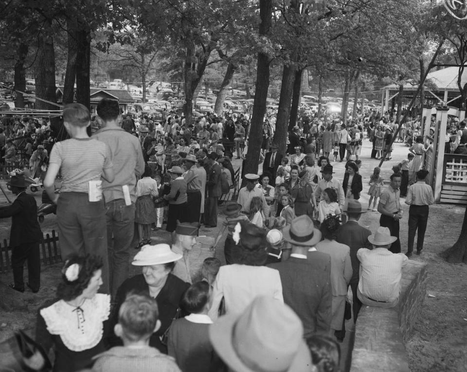 April 7, 1945: The Forest Park Zoo opened Sunday to a big crowd, proving that the thrill of visiting the Zoo never wanes. Pictured is part of the crowd in the amusement park section of the park. They are enjoying the shade from several large trees. An airplane merry-go-round is on the back left.