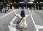 <p>A woman raises her arms as she kneels on a road in front of police officers on the first day of the G-20 summit in Hamburg, northern Germany, Friday, July 7, 2017. (Photo: Matthias Schrader/AP) </p>