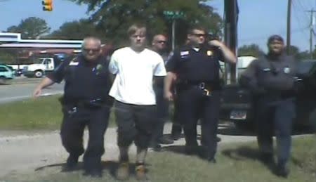 South Carolina shooting suspect Dylann Roof (C) is escorted by police after being detained in Shelby, North Carolina June 18, in this still image from a dash cam video released by the Shelby Police Department June 23, 2015. REUTERS/Shelby Police Department/Handout