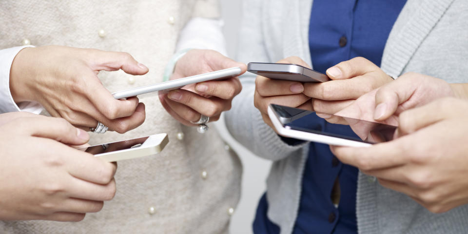 Four adults looking at their smartphones.