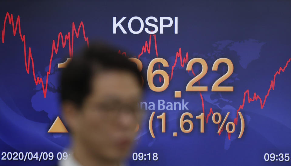 A currency trader walks by the screen showing the Korea Composite Stock Price Index (KOSPI) at the foreign exchange dealing room in Seoul, South Korea, Thursday, April 9, 2020. Asian shares are mixed, with Tokyo lower, as an overnight rally on Wall Street faded. (AP Photo/Lee Jin-man)