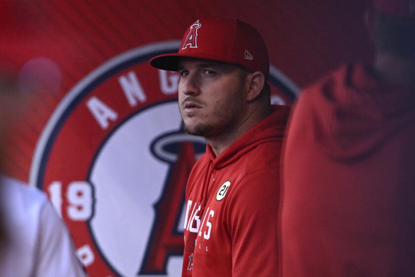 Los Angeles Angels' Mike Trout looks over in the dugout before a baseball game.