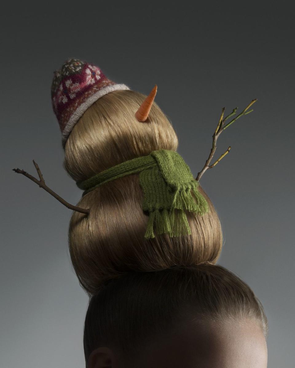 beehive hairstyle segmented into two smooth globes with stick arms sticking out of bottom globe, a green scarf tied between first and second globe, a small carrot sticking out of second globe, which is topped with a small knit cap