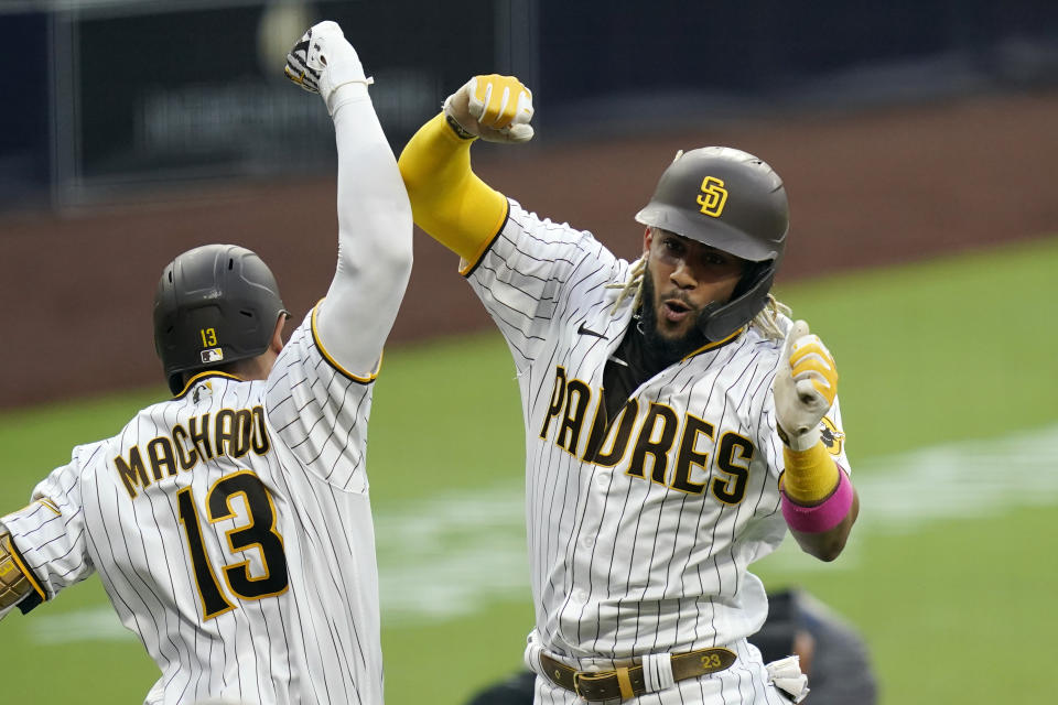 San Diego Padres' Fernando Tatis Jr., right, reacts with teammate Manny Machado (13) after hitting a home run during the third inning of a baseball game against the Texas Rangers, Wednesday, Aug. 19, 2020, in San Diego. (AP Photo/Gregory Bull)