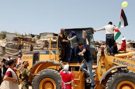 FILE PHOTO: A Palestinian woman argues with an Israeli soldier as she rides on an Israeli bulldozer in the Palestinian Bedouin village of al-Khan al-Ahmar near Jericho in the occupied West Bank July 4, 2018. REUTERS/Mohamad Torokman