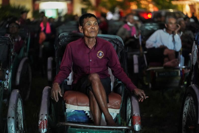 Tricycle drivers attend an outdoor movie screening held by a private organization in Phnom Penh