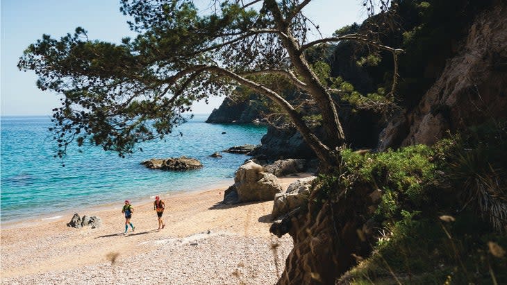 Athletes running along a beach in Girona