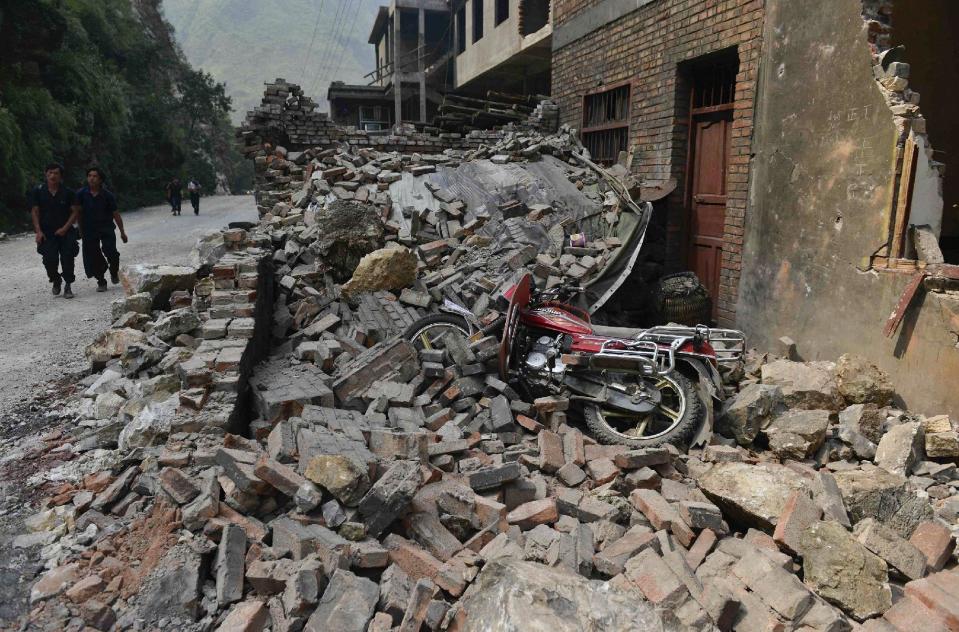 People walk past damaged buildings at a quake-hit Luozehe town in Yiliang county in southwest China's Yunnan province Saturday, Sept. 8, 2012. Rescue workers cleared roads Saturday so they could search for survivors and rush aid to a remote mountainous area of southwestern China after twin earthquakes killed at least 80 people. (AP Photo)