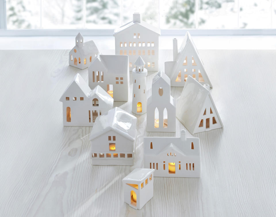 This image provided by Crate & Barrel shows their collection of white ceramic buildings. Crate & Barrel's collection includes alpine homes and hotels as well as midcentury split levels and ranch homes. Add a tealight for a welcoming glow. (Crate & Barrel via AP)