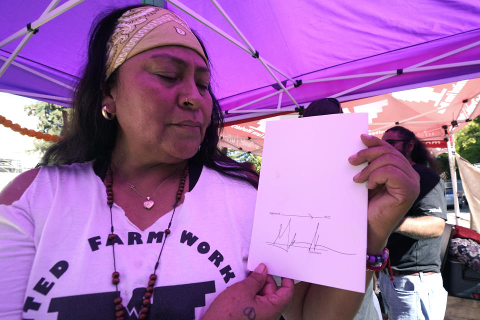 FILE - Farmworker Xochilt Nunez holds a copy of the bill signed by Gov. Gavin Newsom aimed at making it easier for farmworkers to unionize, in Sacramento, Calif., Sept. 28, 2022. One of California's most influential agricultural companies announced Monday, May 13, 2024, that it is suing the state to stop the contentious law to help farmworkers unionize. The legal action by the Wonderful Co. comes as it battles United Farm Workers over a newly formed union at one of its businesses. (AP Photo/Rich Pedroncelli, File)