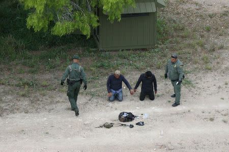 Border patrol agents apprehend people who illegally crossed the border from Mexico into the U.S. in the Rio Grande Valley sector, near Falfurrias, Texas, U.S., April 4, 2018. REUTERS/Loren Elliott