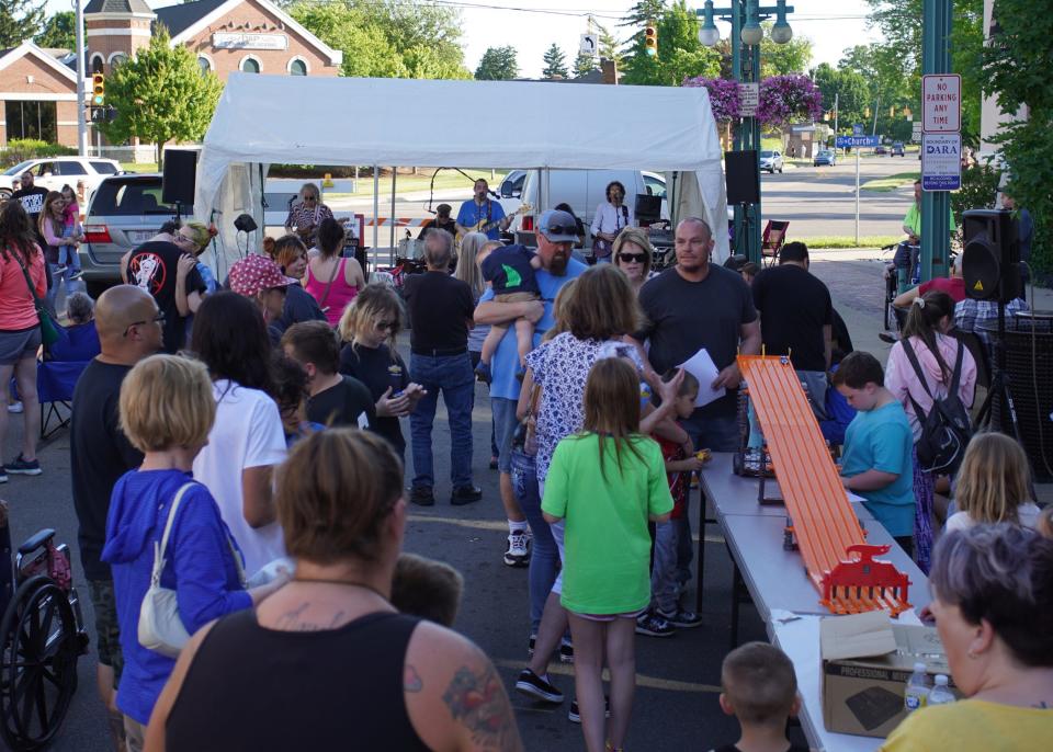 People dance during the June 2022 First Fridays in downtown Adrian while The Metros Band with Gordy Sharpe plays and kids prepare to race Hot Wheels cars.