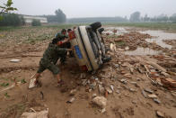 <p>People push a car turned over during floods in Xingtai, Hebei Province, China, July, 24, 2016. (Photo: Stringer/REUTERS)</p>