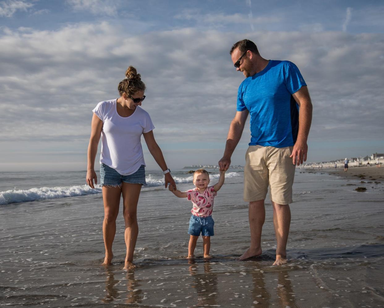 Christina Parisi and Jamie Gosselin of Hampton take their daughter, Sydney, for a morning walk at low tide on Hampton's North Beach Saturday, Aug. 21, 2021.