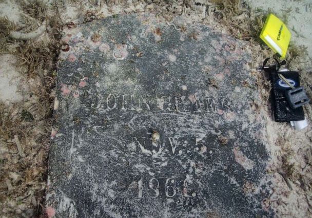 PHOTO: A gravestone with sand shows the inscription 'John Greer. Nov. 5. 1861.' (NPS Photo by C. Sproul)