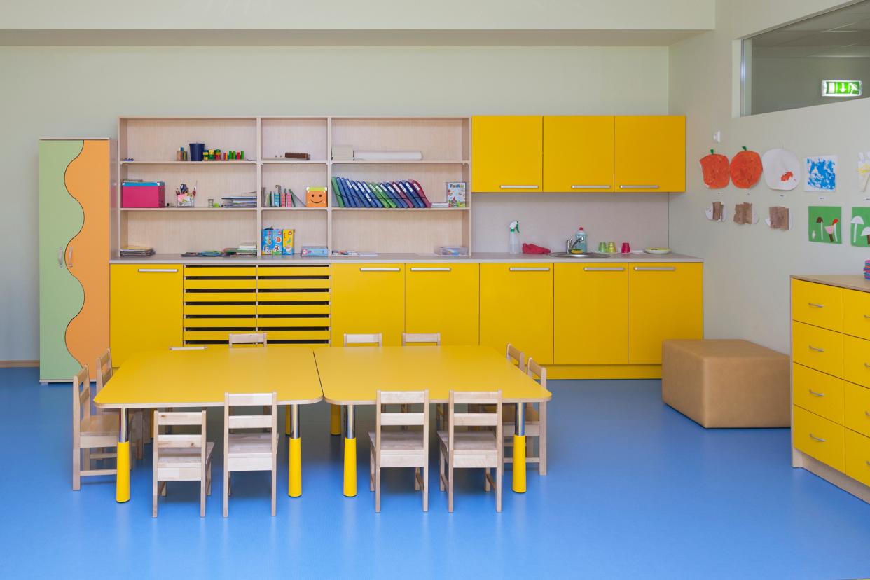 Classroom in a kindergarten school, yellow furniture and tables and blue floor.