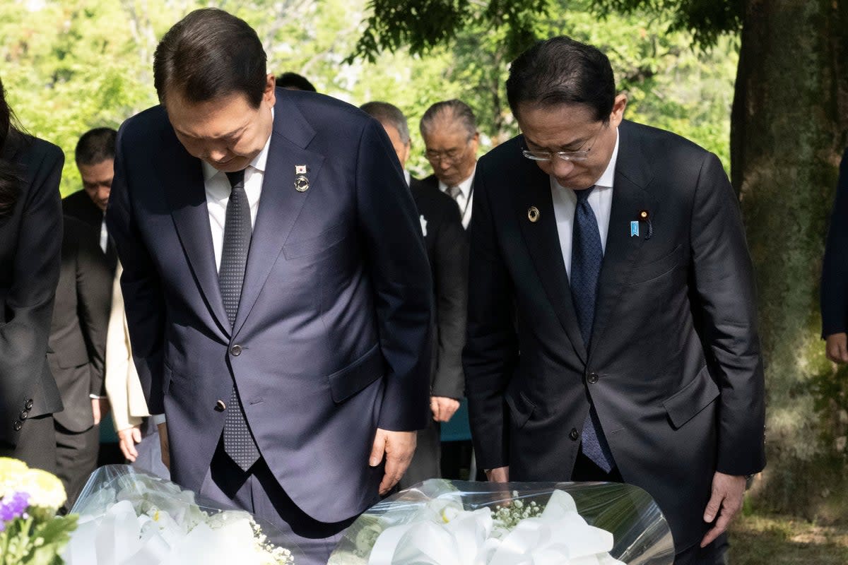 South Korean president Yoon Suk Yeol (L) with Japan’s prime minister Fumio Kishida bow after laying flowers at the Korean Atomic Bomb Victims Memorial Memorial (AP)
