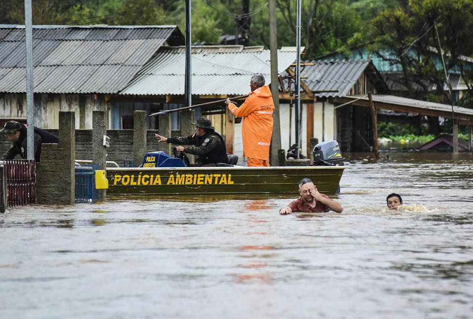 Image: Police officers check a house as residents walk through a flooded street after flooding caused by a cyclone in Passo Fundo, Rio Grande do Sul state, Brazil, on September 4, 2023. (Diogo Zanatta / Futura Press via AP)