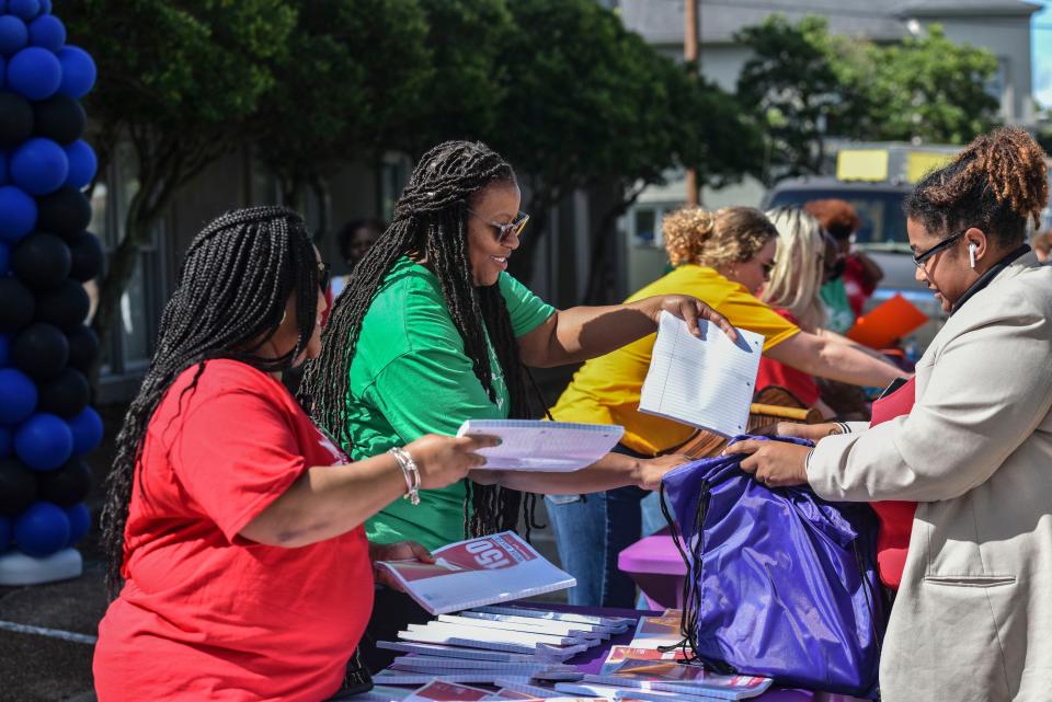 Volunteers give packages of paper to local parents at the Catholic Charities, Inc. school supply giveaway in Jackson on Friday. The giveaway provides access to school supplies for locals in the community.