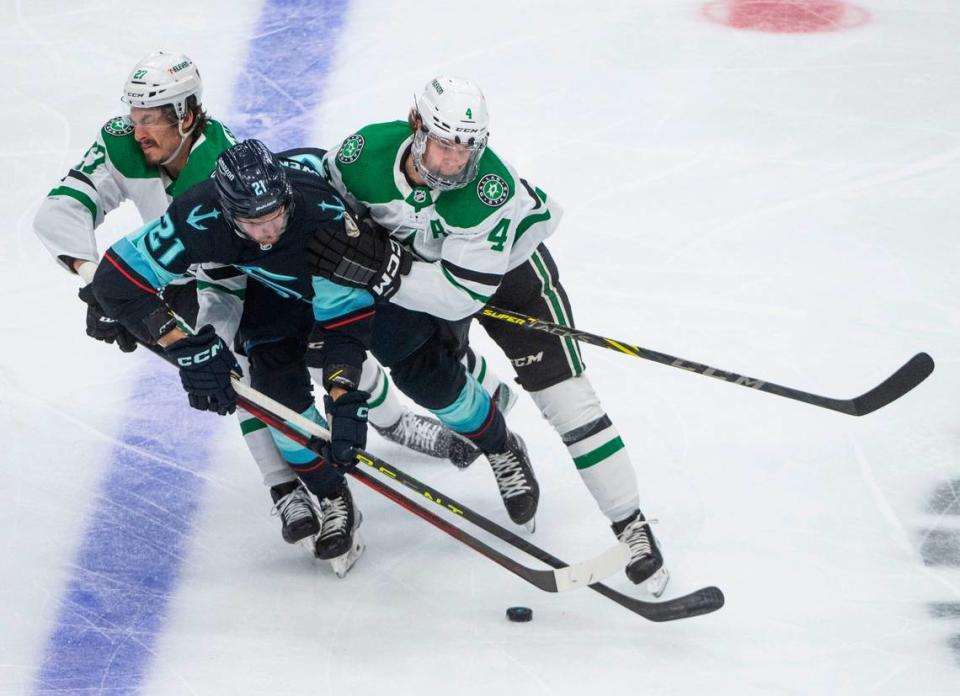 Seattle Kraken center Alex Wennberg (21) tries to keep control of the puck as Dallas Stars left wing Mason Marchment (27) and Dallas Stars defenseman Miro Heiskanen (4) try to shove out of the way during the first period of game four of the second round of the 2023 Stanley Cup Playoffs in Seattle, Wash. on May 9, 2023.