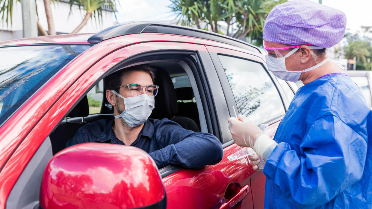 A doctor in a protective suit taking a nasal swab from a person to test for possible coronavirus infection.