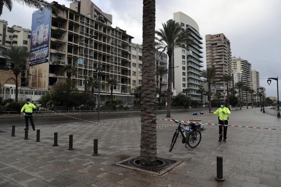 Police bike officers link tape on the empty waterfront promenade as the country starts a new lockdown, in Beirut, Lebanon, Thursday, Jan. 14, 2021. Lebanese authorities began enforcing an 11-day nationwide shutdown and round the clock curfew Thursday, hoping to limit the spread of coronavirus infections spinning out of control after the holiday period. (AP Photo/Bilal Hussein)