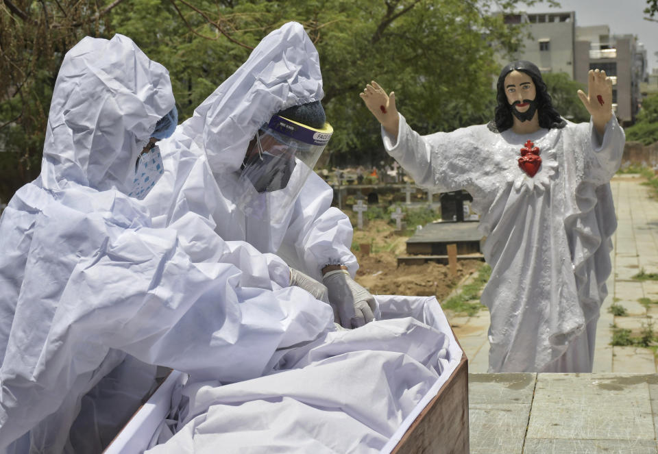 Body of a COVID-19 victim is prepared for burial at a Christian cemetery in New Delhi, India, Saturday, May 29, 2021. India's death toll is the third-highest reported in the world after the U.S. and Brazil. (AP Photo/Ishant Chauhan)