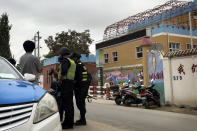 In this Aug. 30, 2018, photo, security personnel inspect camera equipment of journalists outside the Hotan City Kindness Kindergarten, where Meripet learnt her children are kept in Hotan, in western China's Xinjiang region. Meripet lives in exile in Turkey but her family is among tens of thousands swept up in the internment of more than one million Uighurs and other Muslim minorities and there is evidence the government is placing the children of detainees and exiles into dozens of orphanages across Xinjiang. (AP Photo/Ng Han Guan)