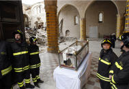 FILE - The salvaged remains of Pope Celestine V are guarded by firefighters after Pope Benedict XVI visited the 13th-century Santa Maria di Collemaggio Basilica, the symbol of the city of L'Aquila, Italy, on April 28, 2009, whose roof partially caved in during an earthquake. During a visit to the earthquake-ravaged city of L’Aquila, Benedict prayed at the tomb of Pope Celestine V, the hermit pope who stepped down in 1294 after just five months in office. Benedict left on Celestine’s tomb a pallium, the simple white woolen stole that is a symbol of the papacy. (AP Photo/Domenico Stinellis, File)