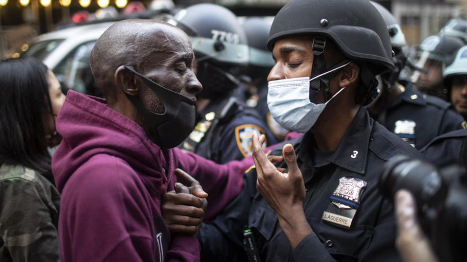 A protester and a police officer shake hands in the middle of a standoff during a solidarity rally