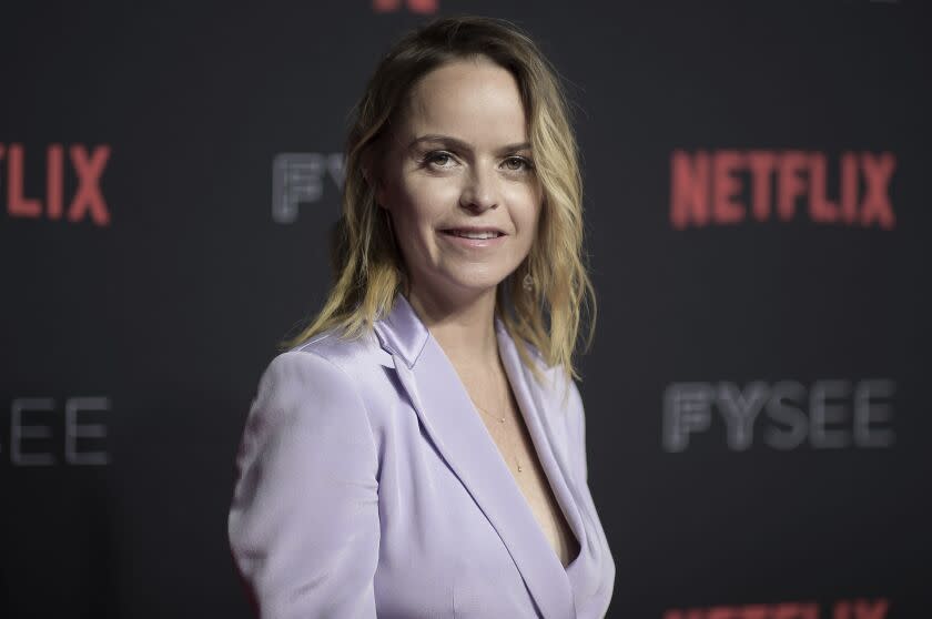 Taryn Manning in a lilac suit jacket posing at an angle at a Netflix red carpet event